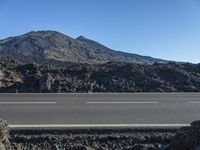 a mountain top with the road in the foreground and rocks around it, and a blue sky and some clouds