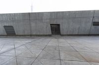 a large gray building with some concrete walls and a closed door in it's center