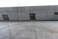 a large gray building with some concrete walls and a closed door in it's center