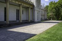 a walkway leading up to a building with several columns on it and grass outside of it