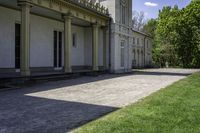 a walkway leading up to a building with several columns on it and grass outside of it