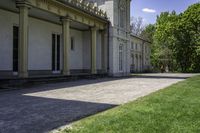 a walkway leading up to a building with several columns on it and grass outside of it