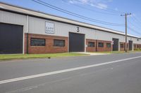 a motorcycle is parked outside of a large industrial building on the side of a road