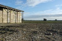 a wooden building sitting next to a big field with green grass growing outside of it