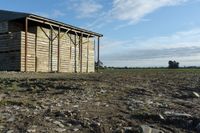 a wooden building sitting next to a big field with green grass growing outside of it