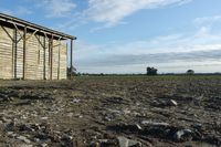 a wooden building sitting next to a big field with green grass growing outside of it