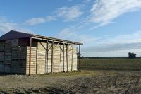 a wooden building sitting next to a big field with green grass growing outside of it