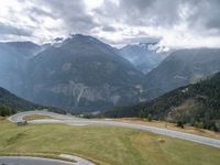 a motorcycle parked in the middle of a road near some mountains with a few people