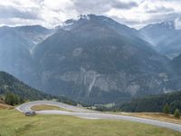 a motorcycle parked in the middle of a road near some mountains with a few people