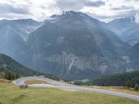 a motorcycle parked in the middle of a road near some mountains with a few people