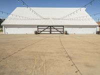 a large white barn with a covered parking lot with lots of lights hanging around it