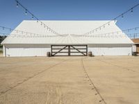 a large white barn with a covered parking lot with lots of lights hanging around it