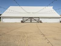 a large white barn with a covered parking lot with lots of lights hanging around it