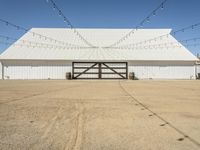 a large white barn with a covered parking lot with lots of lights hanging around it