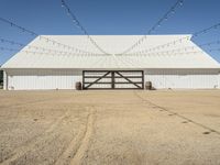 a large white barn with a covered parking lot with lots of lights hanging around it