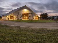 a barn with an entry and door lit up at night with lights on outside it