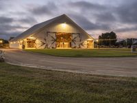 a barn with an entry and door lit up at night with lights on outside it