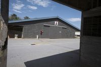 a person standing in front of a barn with a door open next to a tree