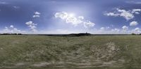 the sun shines brightly in a cloudy, blue sky as seen through an open field