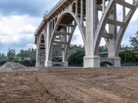 a dirt road with a large bridge in the background under construction at a construction site