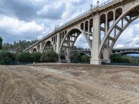 a construction site with a road and bridge in the background a hill with some trees, grass, dirt, and dirt