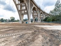 the underpass of a bridge is being built in a lot of dirt in front of trees