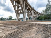 the underpass of a bridge is being built in a lot of dirt in front of trees