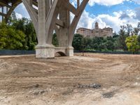 a view of an old bridge and a big building in the background and dirt around it