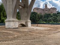 a view of an old bridge and a big building in the background and dirt around it