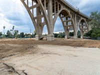 a street under construction with a bridge in the background, as dirt and sand surrounds