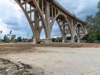 a street under construction with a bridge in the background, as dirt and sand surrounds