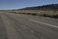 a motorcycle riding down a dirt road with mountains in the distance in the distance is a lone street