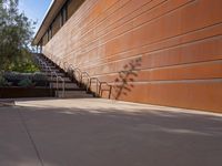 the shadow of a motorcycle is cast on a wall next to steps and trees in front