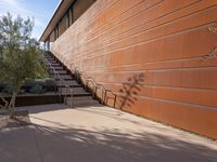 the shadow of a motorcycle is cast on a wall next to steps and trees in front
