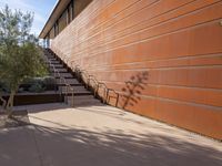 the shadow of a motorcycle is cast on a wall next to steps and trees in front