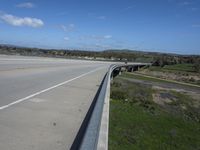 an interstate highway with two lanes going over an obstacle level bridge above the other side