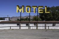 a motel sign in a deserted lot with mountains in the background, taken from a car window