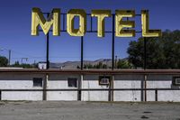 a motel sign in a deserted lot with mountains in the background, taken from a car window