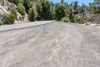 an asphalt road with gravel and rocks along it and trees on either side of it