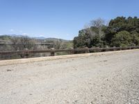 a view from a bridge overlooking trees and a mountain range of hills behind a bridge