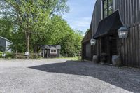 a barn with gravel near by and a horse standing outside it on a farm site