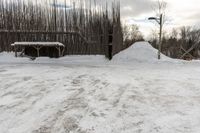 a white snow pile near a wooden fence and a pole in the background and the sky with clouds