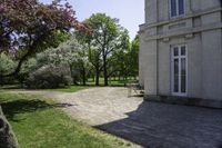 two benches in a park next to a building with trees in the background and a stone path between them