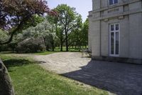 two benches in a park next to a building with trees in the background and a stone path between them