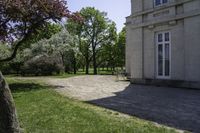 two benches in a park next to a building with trees in the background and a stone path between them