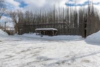 a fence is surrounded by snow outside in the winter in front of a house and some trees