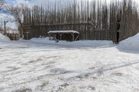 a fence is surrounded by snow outside in the winter in front of a house and some trees