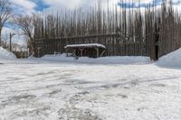 a fence is surrounded by snow outside in the winter in front of a house and some trees