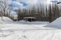 a fence is surrounded by snow outside in the winter in front of a house and some trees