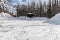 a fence is surrounded by snow outside in the winter in front of a house and some trees